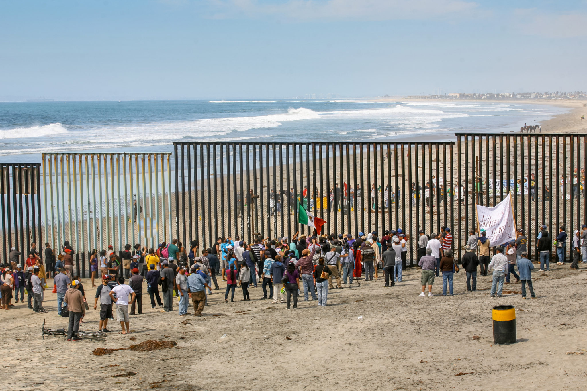 Dozens of migrants and workers on the sides of the US-Mexico border ...